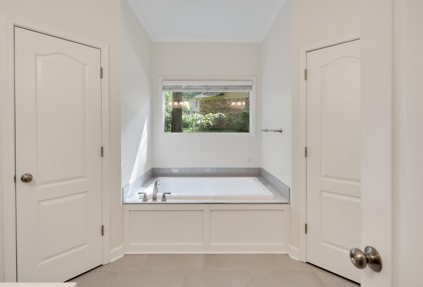 Built-in soaking tub with deck-mounted faucet and a surrounding stone-finish surface