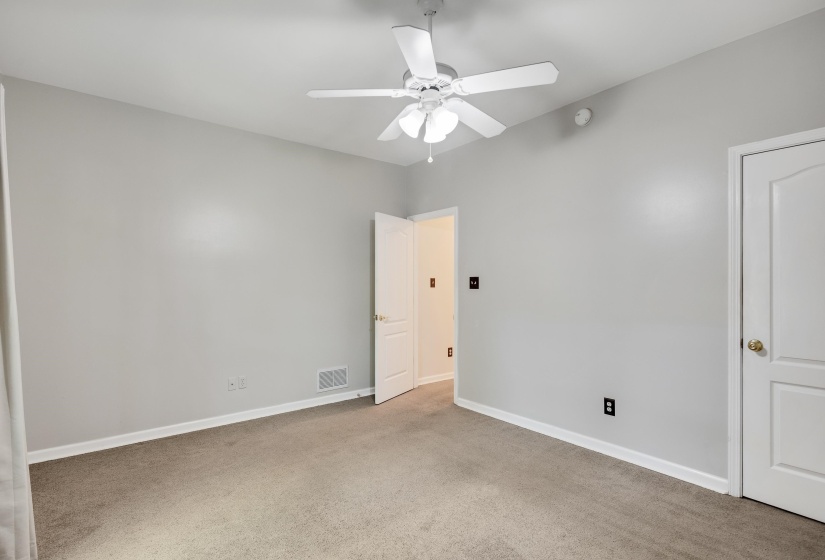 Carpeted interior space featuring a ceiling fan with integrated lighting, light gray wall paint, white trim, and a white interior door