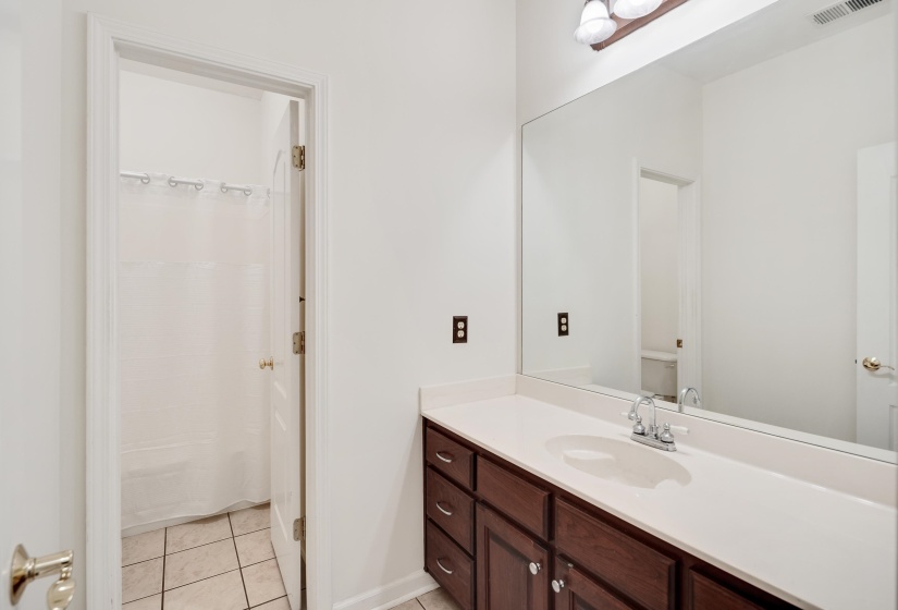 Bathroom featuring a dark wood-finish vanity with a light countertop, an integrated sink, and a large wall-mounted mirror