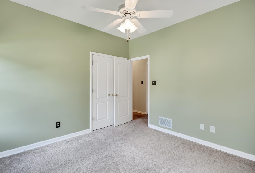Carpeted room with light green walls, white trim, and a ceiling fan with light fixture