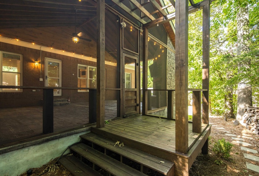 Screened porch featuring a multi-level wood-plank deck, wood railing, and exposed wood beam ceiling