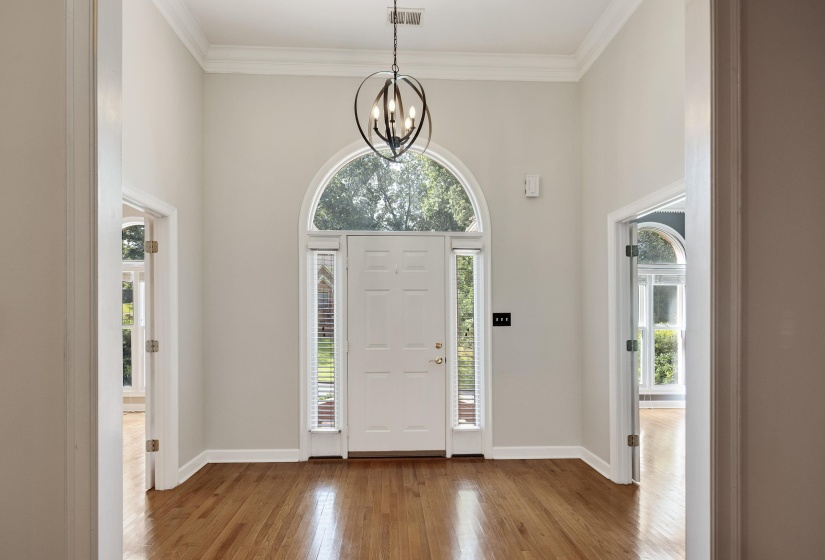 Grand foyer featuring a high ceiling, hardwood flooring, and a decorative spherical chandelier