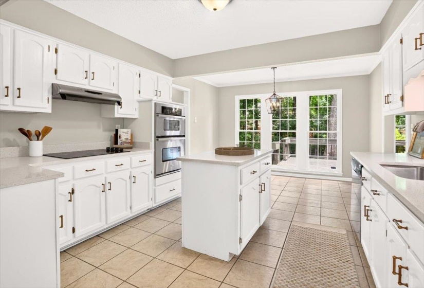 Kitchen featuring white cabinetry, light countertops, stainless steel double ovens, a central island, and tile flooring