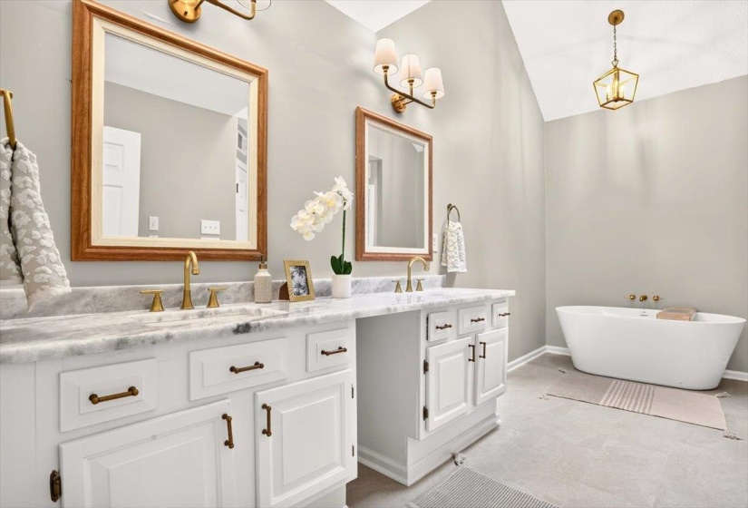Dual vanity with white cabinetry, brass hardware, and stone countertops