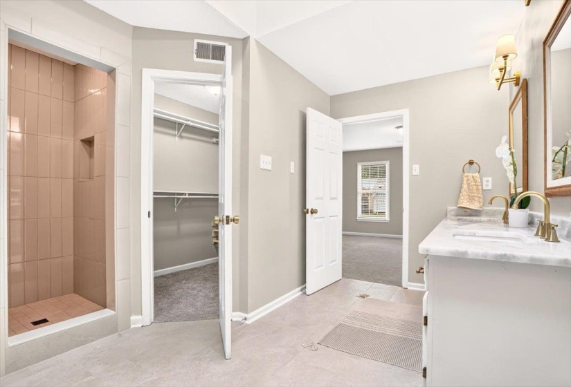 Bathroom featuring a double vanity with stone countertop, gold-finish fixtures, and a framed mirror