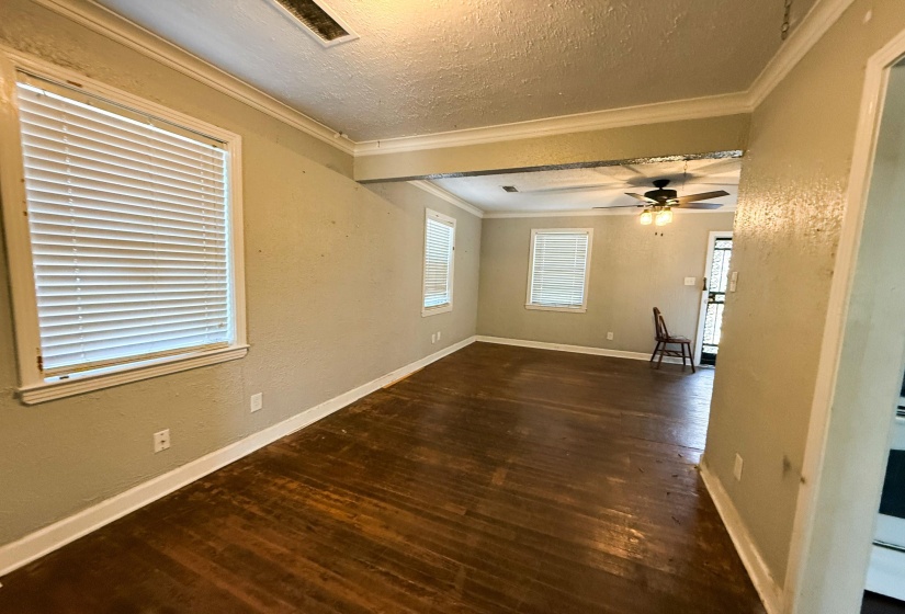 Empty room with dark wood finished floors, a textured wall, a textured ceiling, ornamental molding, and ceiling fan