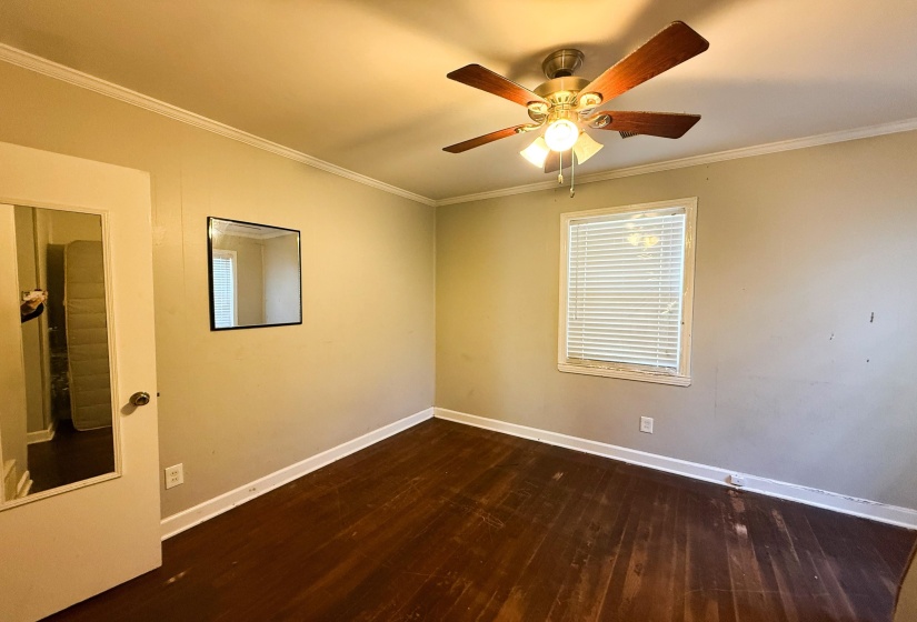 Empty room with dark wood-style flooring, ornamental molding, and a ceiling fan