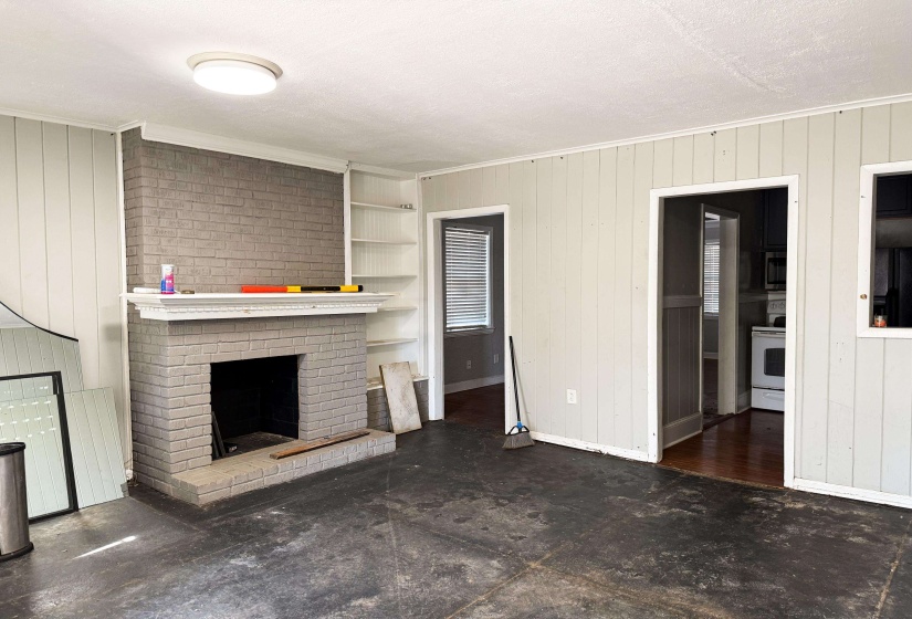 Unfurnished living room with a fireplace, crown molding, wooden walls, and a textured ceiling
