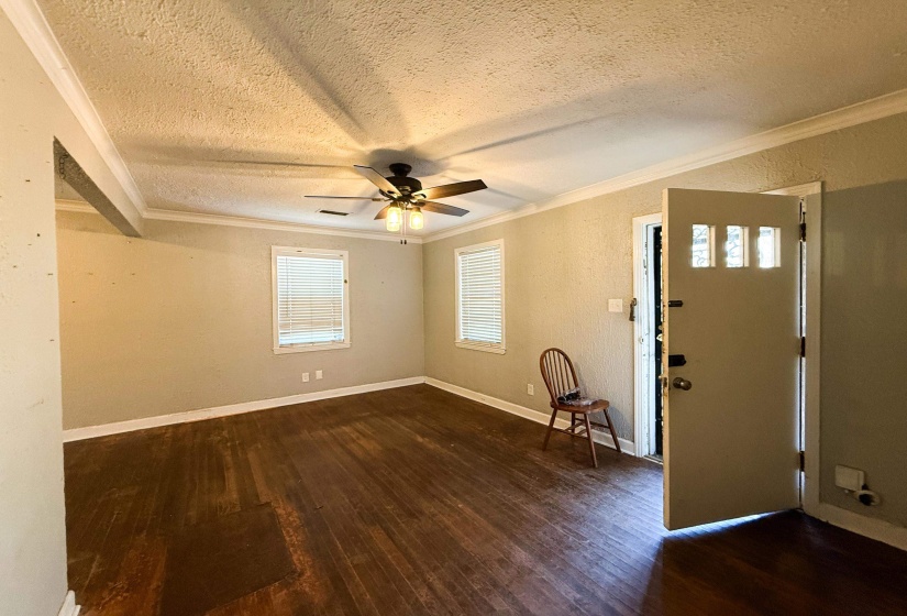 Entrance foyer with dark wood-style floors, a textured wall, ceiling fan, a textured ceiling, and crown molding