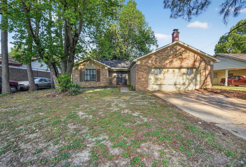 Ranch-style home with brick siding, an attached garage, a chimney, and driveway