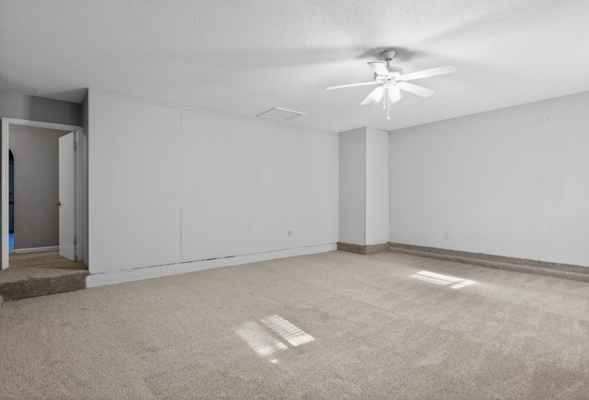 Unfurnished room featuring light carpet, a ceiling fan, and a textured ceiling