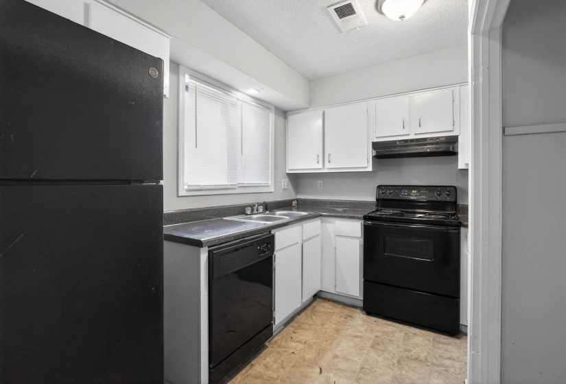 Kitchen featuring dark countertops, black appliances, white cabinetry, and a textured ceiling