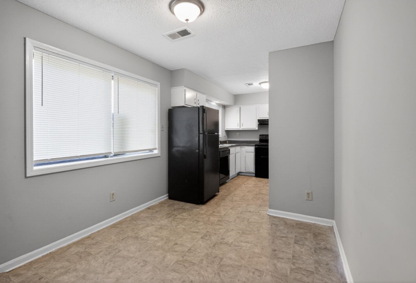 Kitchen with black appliances, white cabinetry, and a textured ceiling