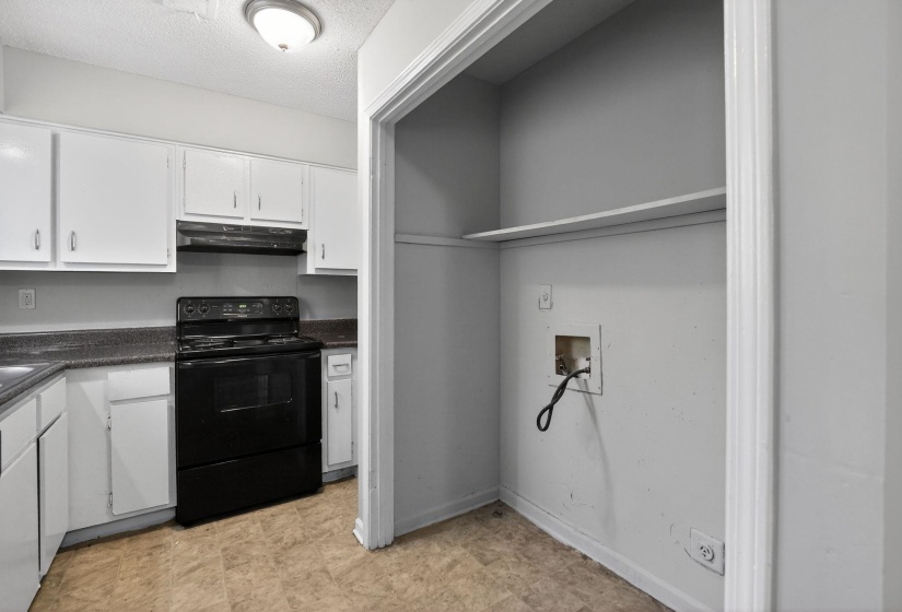 Kitchen featuring black electric range oven, white cabinets, and a textured ceiling