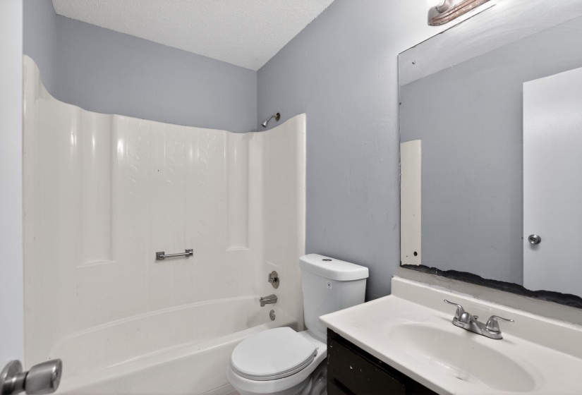 Bathroom featuring vanity,  shower combination, and a textured ceiling