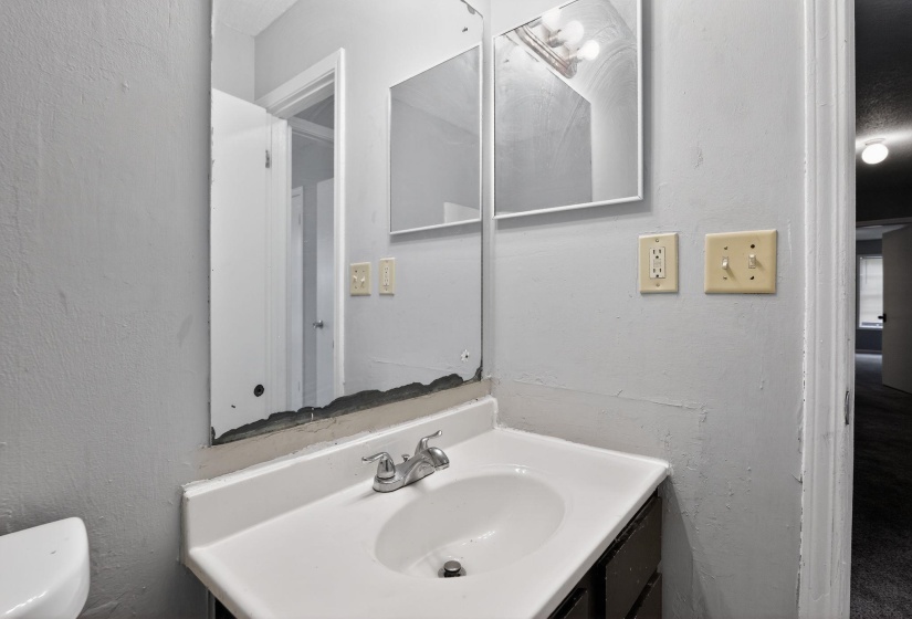 Bathroom with a textured wall and vanity