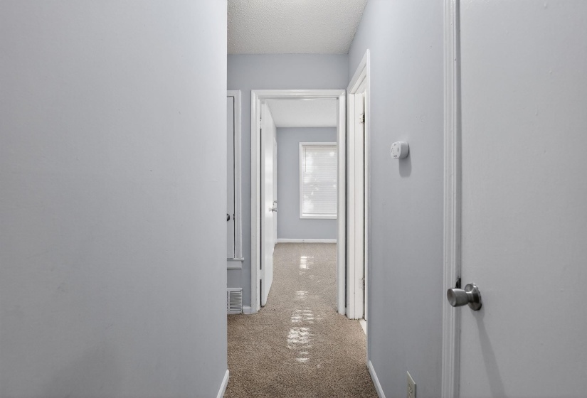 Corridor with a textured ceiling and light carpet