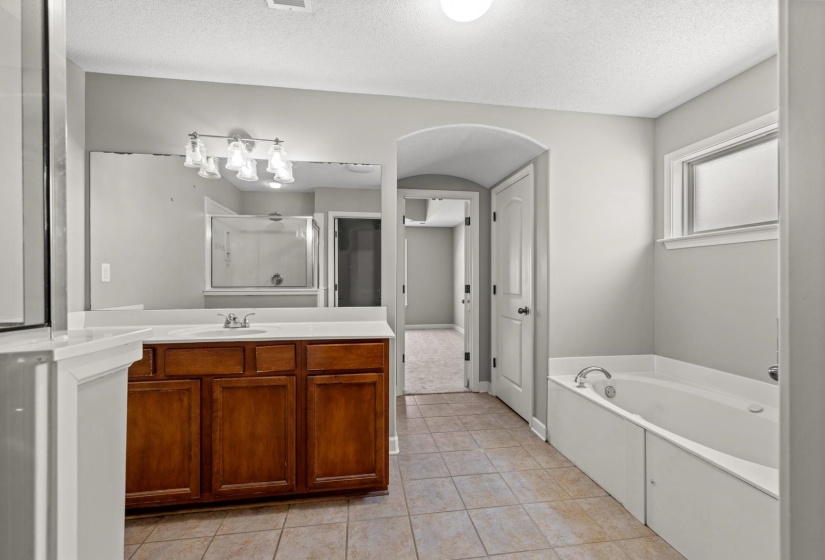 Bathroom featuring a single vanity with wood cabinetry, a large wall-mounted mirror, and a white countertop