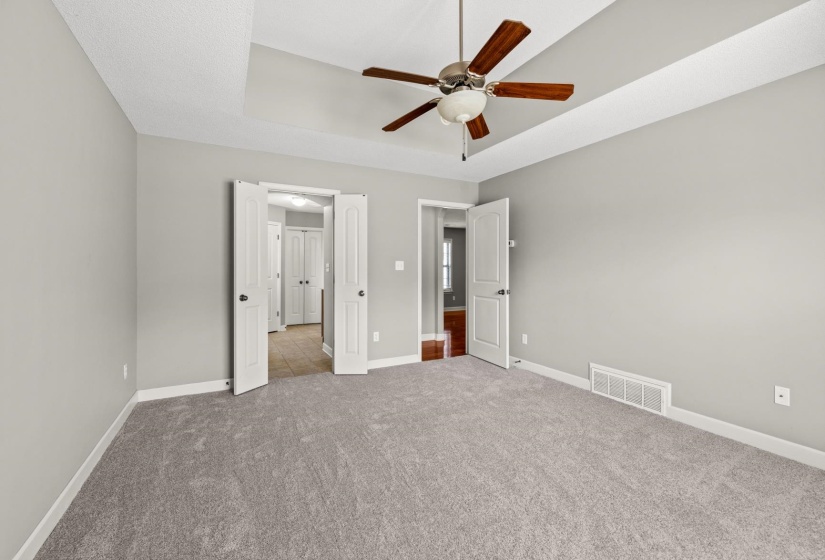 Spacious room featuring tray ceilings, neutral carpeting, and light gray walls