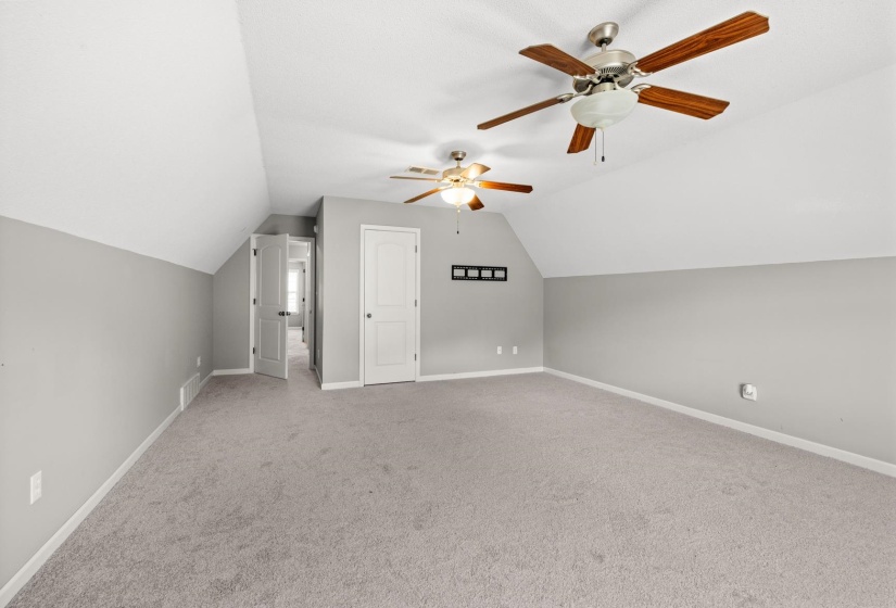Spacious room with sloped ceilings and neutral gray walls
