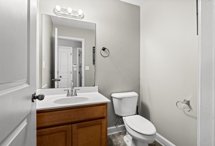 Bathroom featuring a wood-finish vanity with a white countertop and integrated sink, a rectangular mirror, and a three-light vanity fixture