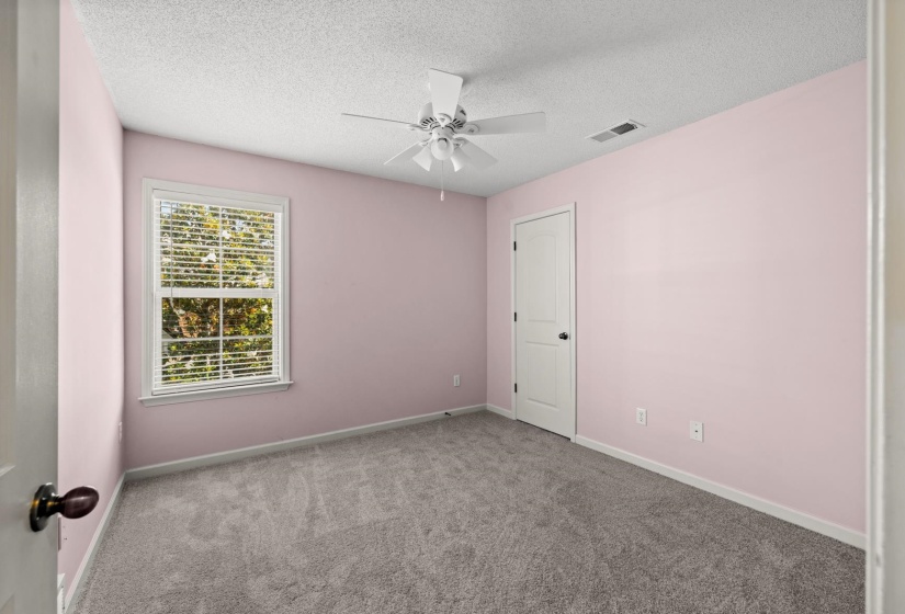 Bedroom featuring light pink walls, gray carpet flooring, a white ceiling fan, and a single window with blinds