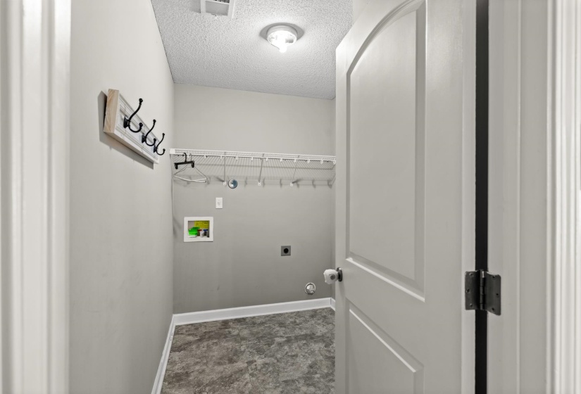 Dedicated laundry area with utility hookups and wire shelving