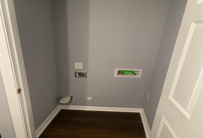 Dedicated laundry area featuring modern gray walls, dark wood-finish flooring, and white baseboards