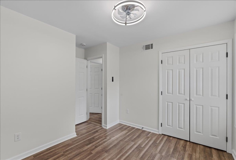 Bright interior room featuring wood-finish flooring and a contemporary ceiling fan with integrated lighting
