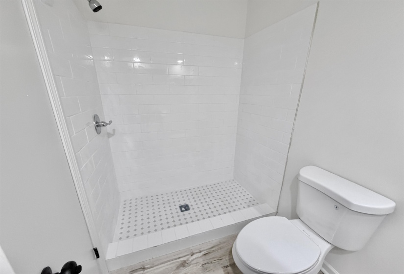 Walk-in shower with white subway tile surround and a tiled floor with a decorative pattern