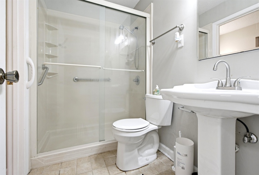Shower enclosure with sliding glass doors and grab bars