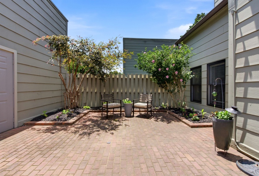 Brick paver patio featuring raised garden beds, a privacy fence, and mature landscaping