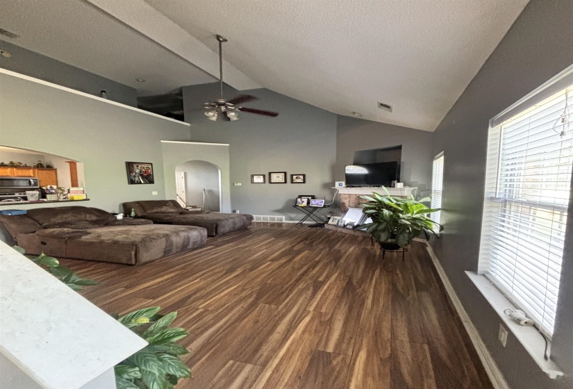 Spacious living area featuring high vaulted ceilings, wood-finish flooring, and a ceiling fan
