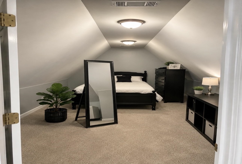 Carpeted room featuring a sloped ceiling design, flush-mount lighting fixtures, and light gray wall paint with a white trim accent