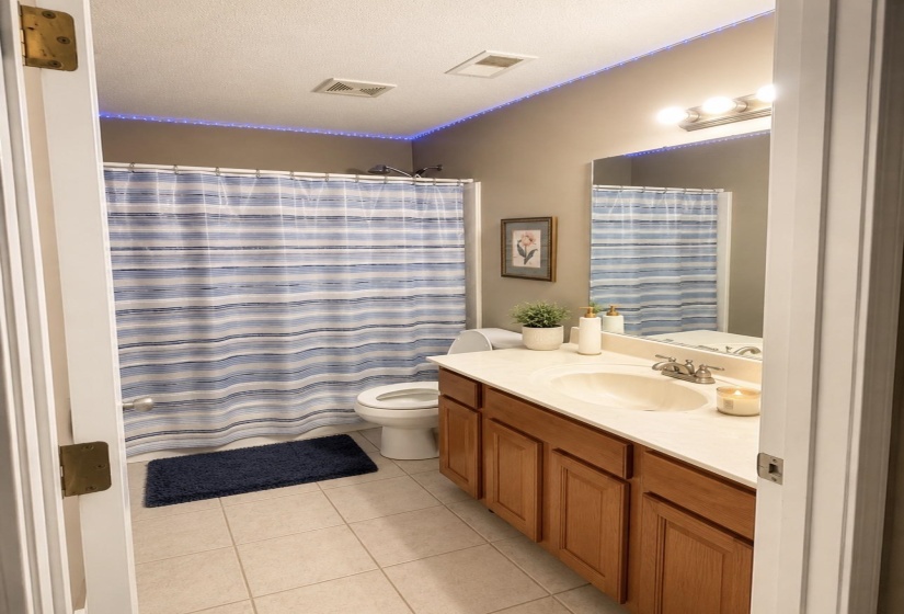 Bathroom featuring a vanity with a light-toned countertop, wood-finish cabinetry, and an integrated sink