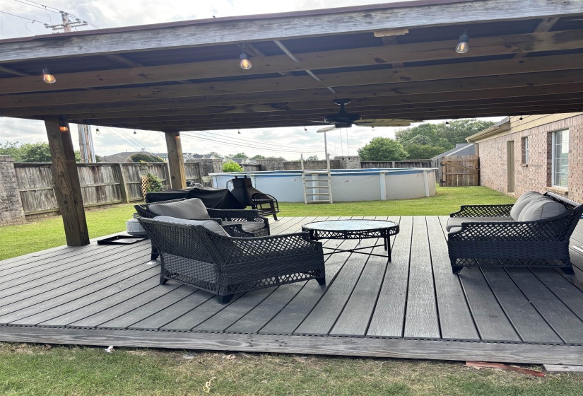 Covered deck featuring composite decking, exposed wood beams, and string lighting