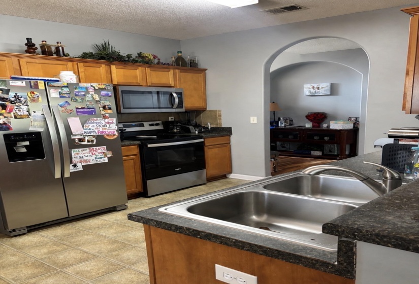 Kitchen featuring light wood cabinetry, stone-finish countertops, and tile flooring