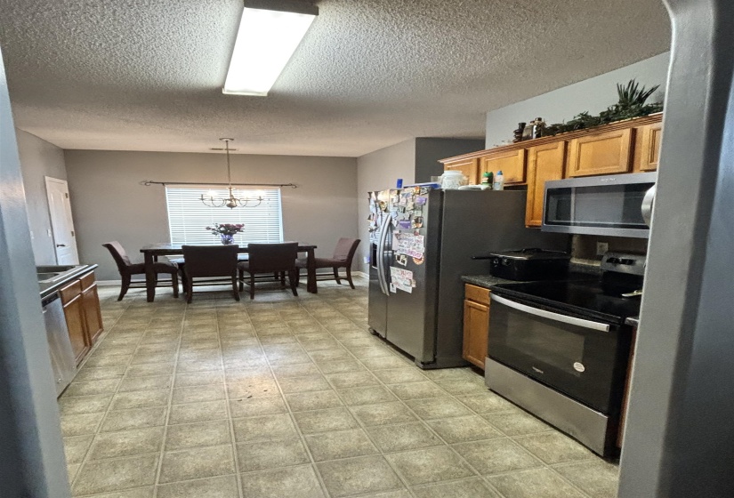 Kitchen and dining area featuring square tile flooring, wood cabinetry, built-in microwave, and stainless steel appliances