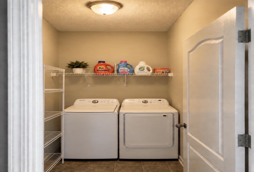 Dedicated laundry space featuring a white wire shelving system, a single wall-mounted shelf, and neutral-toned floor tiling