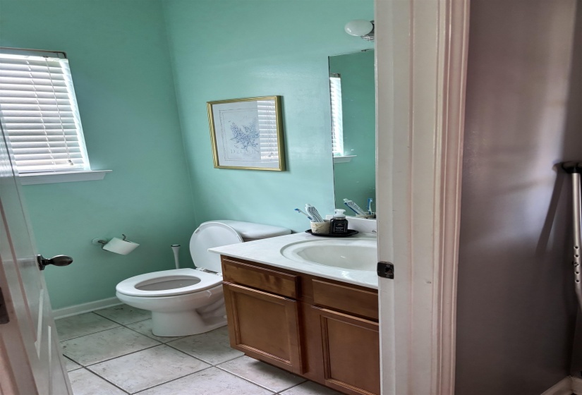 Powder room featuring a single vanity with wood-finish cabinetry, a ceramic basin, and a light-toned countertop