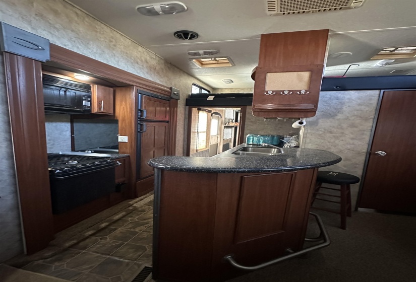 Kitchen with gas range, dark countertops, a sink, black microwave, and a peninsula