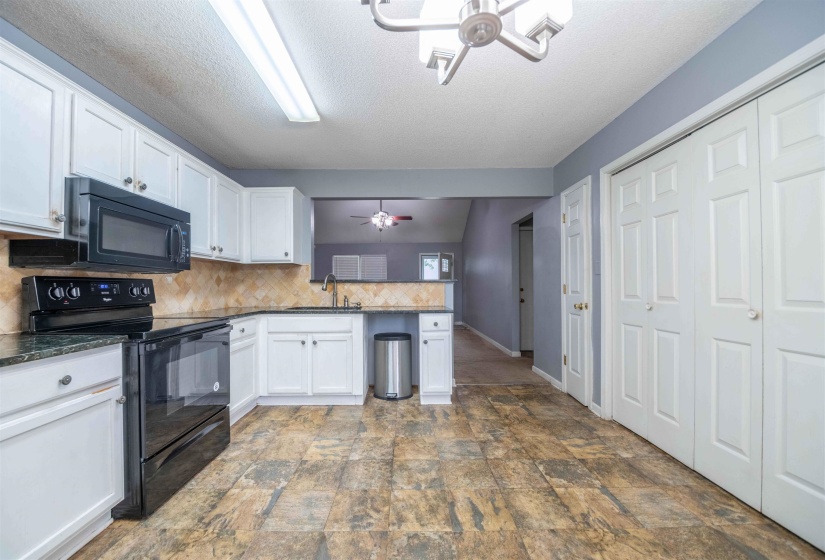 Kitchen featuring white cabinetry, black appliances, a tile backsplash, and wood-finish flooring