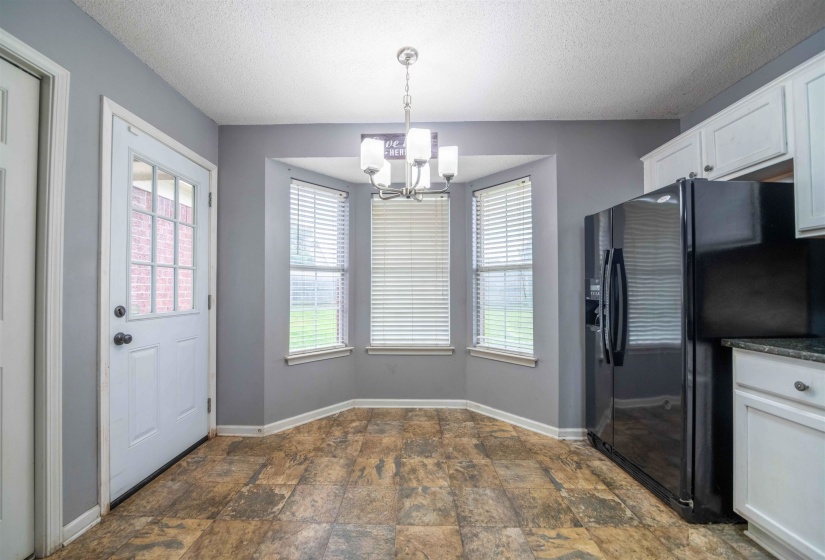 Eat-in kitchen area featuring a bay window, wood-finish flooring, and a chandelier light fixture
