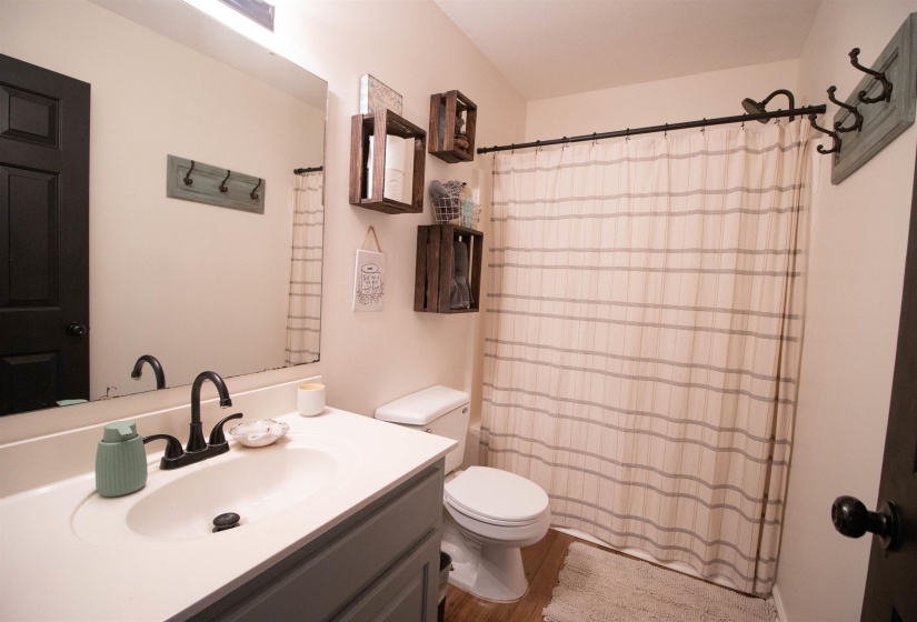 Bathroom featuring a single vanity with an integrated sink, dark bronze hardware, a full-width mirror, and wood-finish flooring