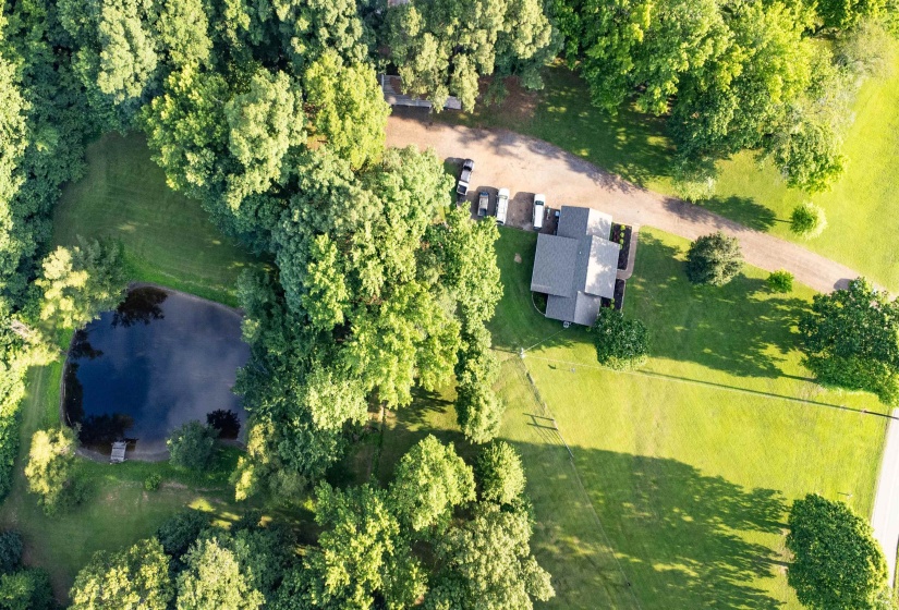 Expansive property featuring a private pond with a small dock, surrounded by mature trees