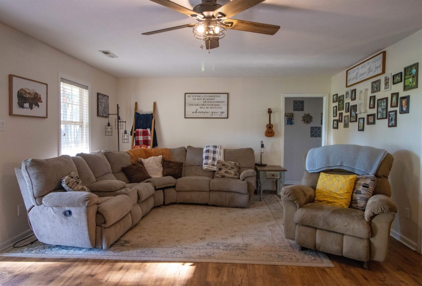 Spacious Great Room featuring wood-finish flooring and a ceiling fan with integrated lighting