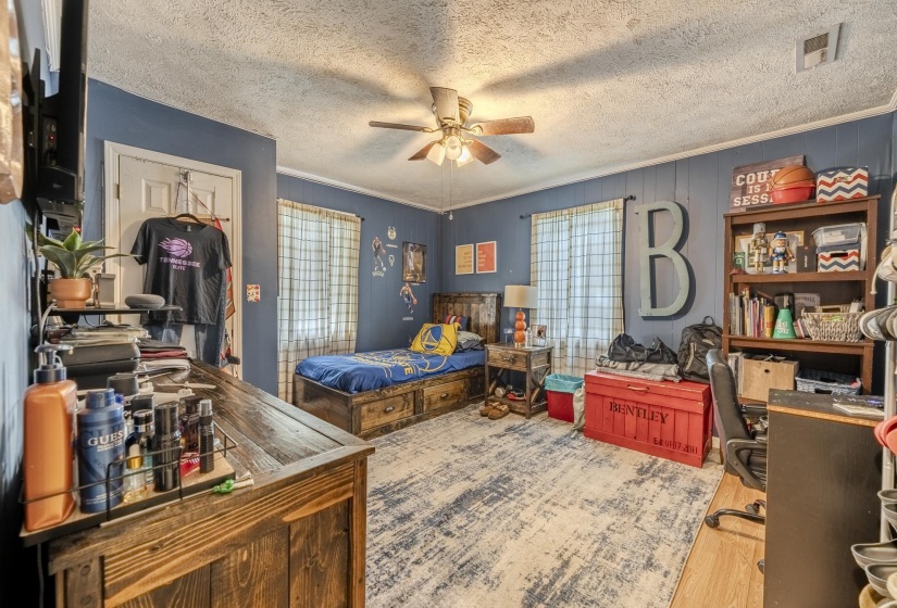 Room featuring wood-finish flooring, a ceiling fan, and painted paneling