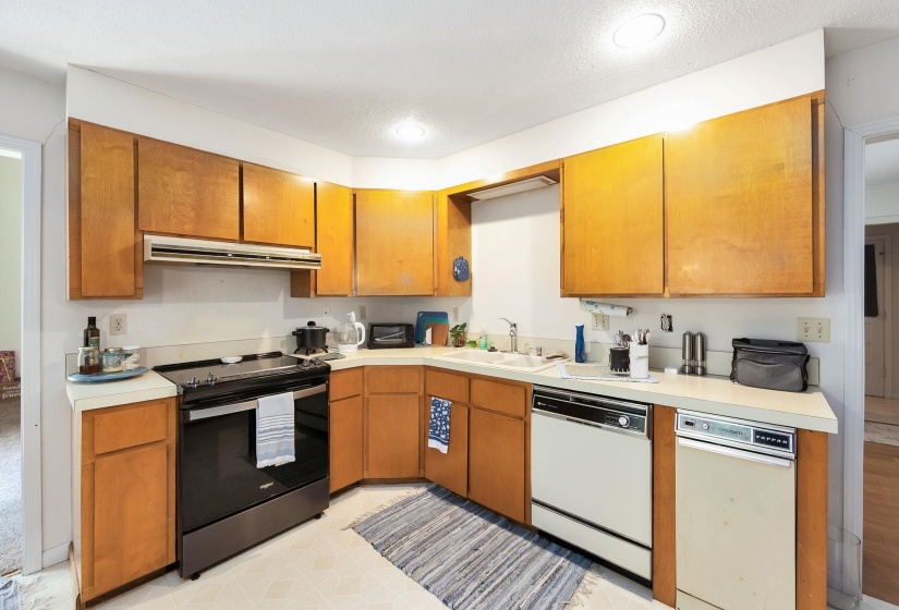 Kitchen featuring wood cabinetry, light-toned countertops, a black range, and dual dishwashers