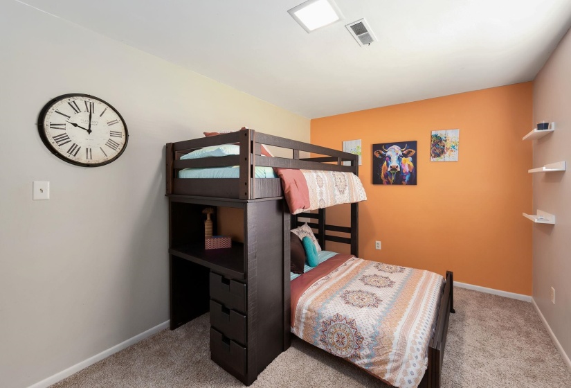 Carpeted room featuring a ceiling-mounted light fixture, warm orange accent wall, and light-toned walls