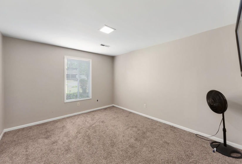 Carpeted room featuring neutral wall paint, white trim, a single window with blinds, and recessed lighting